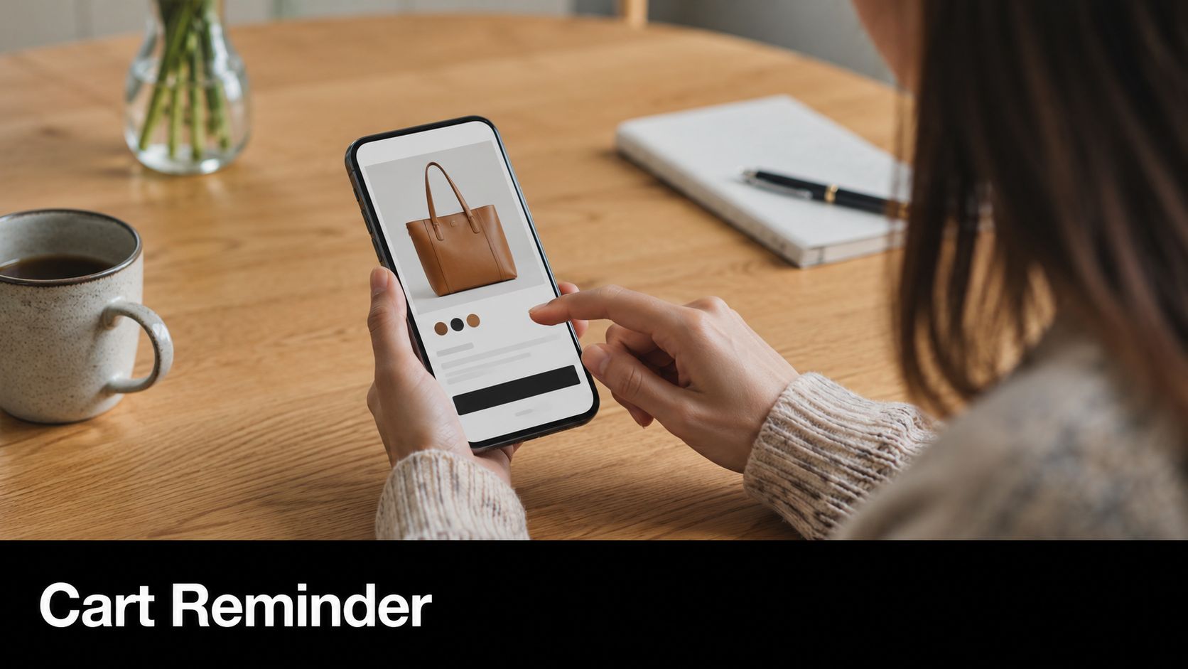 A person using a smartphone to shop online for a brown leather handbag while sitting at a desk.