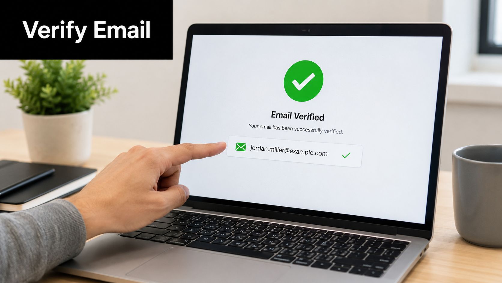 A person pointing to a laptop screen showing a successful email verification message for Jordan Miller.